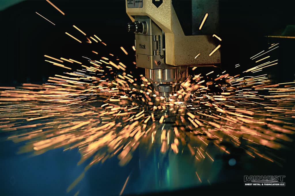 Industrial CNC fiber laser cutting machine cutting sheet metal with sparks at Midwest Sheet Metal & Fabrication in Greenville, Wisconsin.